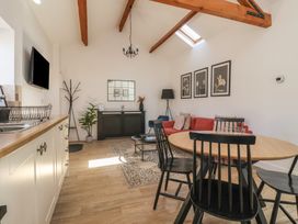 A kitchen and living room area with a round wooden dining table and black chairs a red sofa a black cabinet and wooden ceiling beams at Guillemot in Flamborough