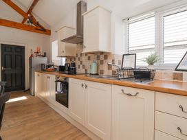 A kitchen with cabinets a sink a window and a black door at Guillemot in Flamborough