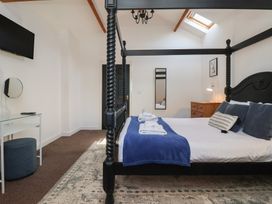 A bedroom with a four poster bed a rug a chest of drawers and a wall mounted television at Guillemot in Flamborough