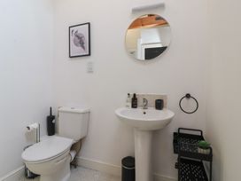 A bathroom with a toilet sink round mirror and a storage rack at Guillemot in Flamborough
