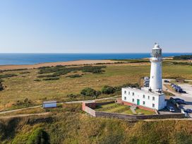 A lighthouse by the ocean with parked cars at Guillemot in Flamborough