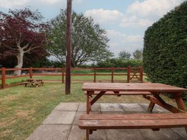 A garden with a wooden table and bench at Puffin in Flamborough