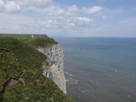 A grassy cliff overlooking the ocean with a walking path and people at Kittiwake in Flamborough