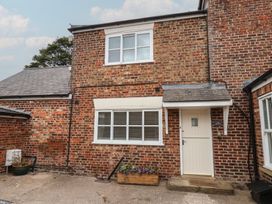 An exterior view of a red brick building with a door and flower box at The Pheasantry in Flamborough