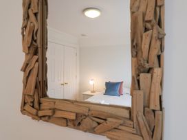 A bedroom with a mirror reflecting a bed and lamp at 9 Church Farm Rise in Aldeburgh