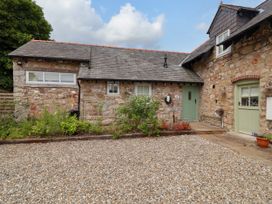 A stone building with a gravel area and plants at The Barn in Tafarn-Y-Gelyn
