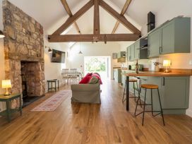 A living room with a sofa and kitchen area at The Barn in Tafarn-Y-Gelyn