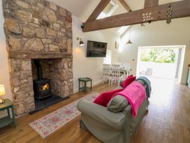 A living room with a stone fireplace and wood stove at The Barn in Tafarn-Y-Gelyn