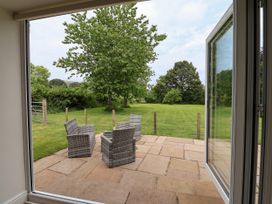 An outdoor patio area with chairs overlooking a grassy field at The Barn Tafarn-Y-Gelyn