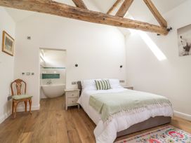 A bedroom with a bed and a bathroom view at The Barn in Tafarn-Y-Gelyn