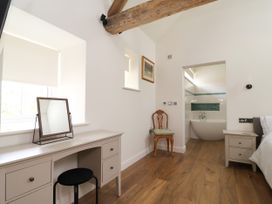 A bedroom with a desk and chair near a bathroom entrance at The Barn in Tafarn-Y-Gelyn
