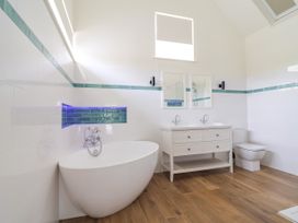 A bathroom with a bathtub, washbasin, and toilet at The Barn in Tafarn-Y-Gelyn