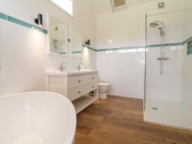 A bathroom with a bathtub, sink, and shower at The Barn in Tafarn-Y-Gelyn