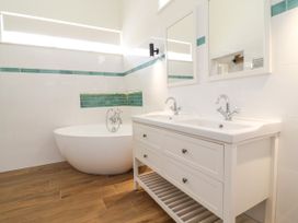 A bathroom with a bathtub and double vanity at The Barn Tafarn-Y-Gelyn