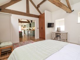 A bedroom with a desk and television leading to a kitchen at The Barn in Tafarn-Y-Gelyn