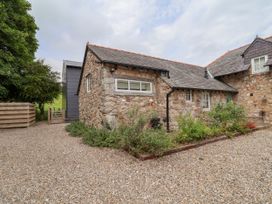A view of a stone building with a gravel driveway at The Barn in Tafarn-Y-Gelyn