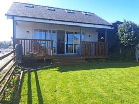 A house with a wooden deck and steps leading to a lawn at Capel Park (Tyddynod Bach) in Llandyfrydog near Llanerchymedd