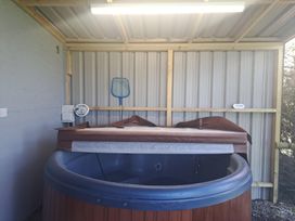 A covered hot tub with a partially removed cover in a shed with a blue pool net hanging on the wall at Capel Park (Tyddynod Bach) in Llandyfrydog near Llanerchymedd