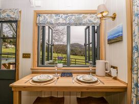 A dining table set for two with plates forks knives glasses and a kettle by a window with a view of fields at Evendine Hut at Evendine Cottage in Colwall Herefordshire