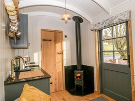 A small kitchen area with a wood stove and a door with a window at Evendine Hut @ Evendine Cottage in Colwall Herefordshire