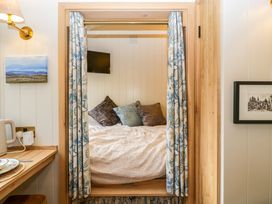 A small sleeping nook with a bed and pillows and a mounted tv at Evendine Hut @ Evendine Cottage in Colwall Herefordshire
