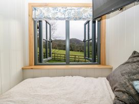 A bedroom with a bed near an open window showing a countryside view at Evendine Hut @ Evendine Cottage in Colwall Herefordshire