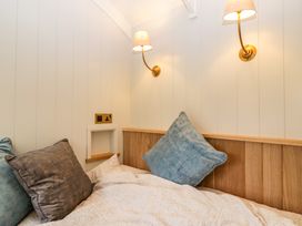 A bed with blue and brown pillows against a wood paneled wall with two wall lamps at Evendine Hut @ Evendine Cottage Colwall Herefordshire