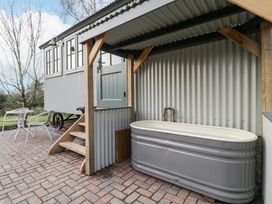 An outdoor covered area with a bathtub and steps leading to a raised door beside a small table and chairs Evendine Hut @ Evendine Cottage Colwall Herefordshire