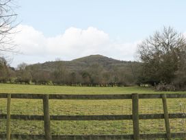 A grassy field with a wooden fence and trees in the background with a hill at Evendine Hut @ Evendine Cottage in Colwall Herefordshire