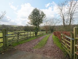 A gravel driveway with wooden gates and fences alongside trees and fields at Evendine Hut @ Evendine Cottage in Colwall Herefordshire