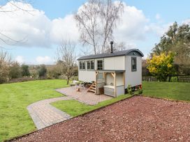 A small shed on wheels with stairs and outdoor seating on a paved area in a garden at Evendine Hut @ Evendine Cottage in Colwall Herefordshire
