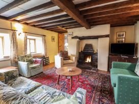 A living room with wooden beams a fireplace a red carpet and sofas at The Long House in Penmachno
