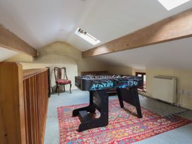 A loft room with a foosball table a wooden chair a bed and a radiator at The Long House in Penmachno