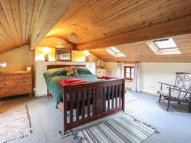 A bedroom with a wooden bed green bedding and red towels under skylight windows at The Long House in Penmachno