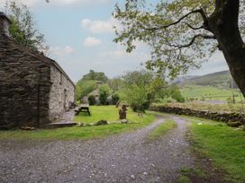 An outdoor scene with a stone building and gravel path at The Long House Penmachno