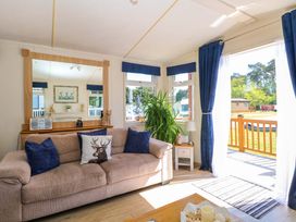 A living room with a sofa, mirror, and plant at 25 Foxburrow Hang in Fritton near Belton