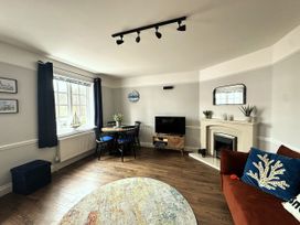 A living room with a table and chairs and a television at Melanie's Cottage in Brewers Quay Harbour