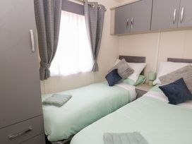 A bedroom with two single beds and grey curtains at The Haven