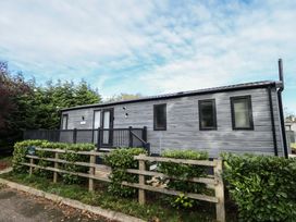 A house with a deck and fence at Heather William Lodge near Woodhall Spa