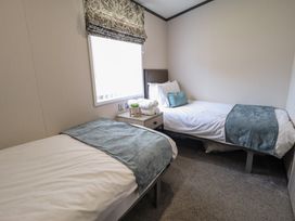 A bedroom with two single beds and a nightstand at Heather William Lodge near Woodhall Spa