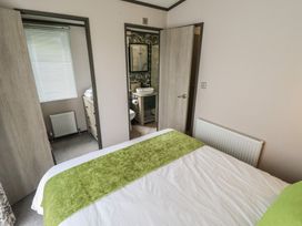 A bedroom with a door leading to a bathroom at Heather William Lodge near Woodhall Spa