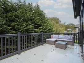 A deck area with a couch and a coffee table at Heather William Lodge near Woodhall Spa