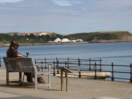A statue seated on a bench overlooking the sea at Evergreen Pines in Cayton Bay near Scarborough