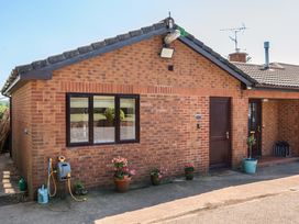 An exterior view of a brick house with flower pots at Piglet Corner in Culmstock