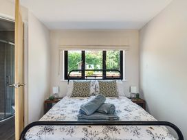 A bedroom with a bed, nightstands, and window view at Piglet Corner in Culmstock