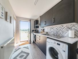 A kitchen with cabinets and a washing machine at Piglet Corner in Culmstock