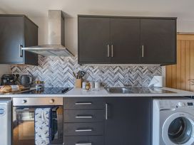 A kitchen with cabinets, stove, sink, and washing machine at Piglet Corner in Culmstock