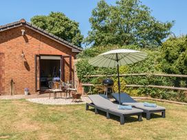 A garden with lounge chairs, table, and barbecue at Piglet Corner in Culmstock