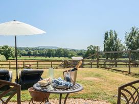 An outdoor area with table and chairs overlooking a field at Piglet Corner in Culmstock