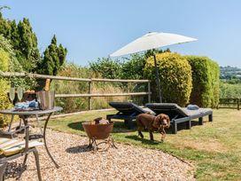 An outdoor area with sun loungers and a table at Piglet Corner in Culmstock